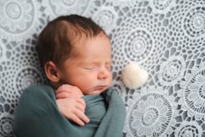 schlafendes neugeborenes liegt gepuckt auf einer weißen Decke